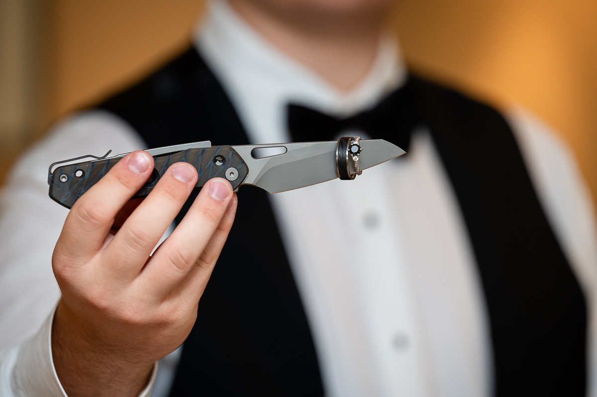 groom prep, ring shot, ring on knife, black wedding dress, 