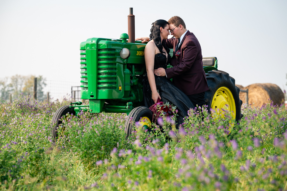 couple posing, Landry lake ranch, horse wedding, black wedding dress wedding, photographer near me, John deer tractor, flowers by above, wedding bouquet, 