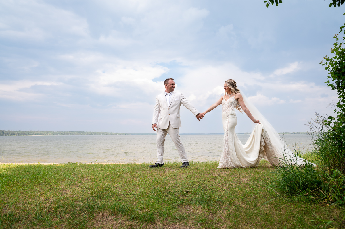veil shot, wedding kiss, wedding dress, beach wedding, franchere bay campground, groom leading bride, wide shot, wedding photography, unique wedding photographer, storming wedding, Bonnyville photographer, photographer near me,